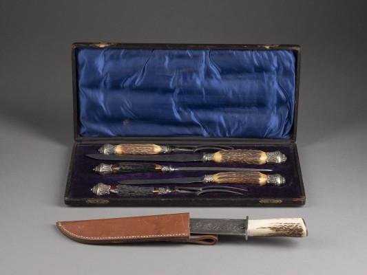 Auction <br>FÜNFTEILIGES TRANCHIERBESTECK MIT HORNGRIFFEN IN ORIGINAL-ETUI UND JAGDMESSER MIT LEDERSCHEIDE