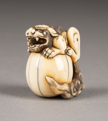 Auktion 143<br>EIN FEINES GESCHNEIDERTES NETSUKE EINES SHISHI MIT KUGEL AUS ELFENBEIN
