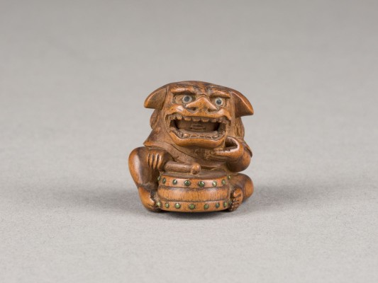 Auction 148<br>EIN GESCHNITZTES NETSUKE EINES TROMMELNDEN SHISHI AUS HOLZ