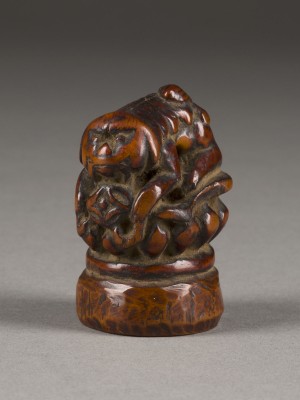 Bild EIN NETSUKE VON SHISHI AUF EINEM LOTUSSOCKEL AUS HOLZ