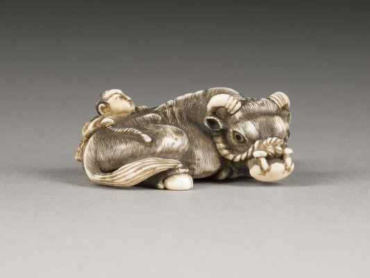 Bild EIN FEINES GESCHNITZTES NETSUKE EINES LIEGENDEN OCHSEN MIT KNABE AUS ELFENBEIN